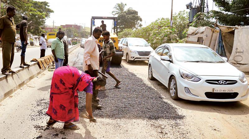 BBMP workers filling potholes at Koramangala near Ejipura in Bengaluru on Tuesday.