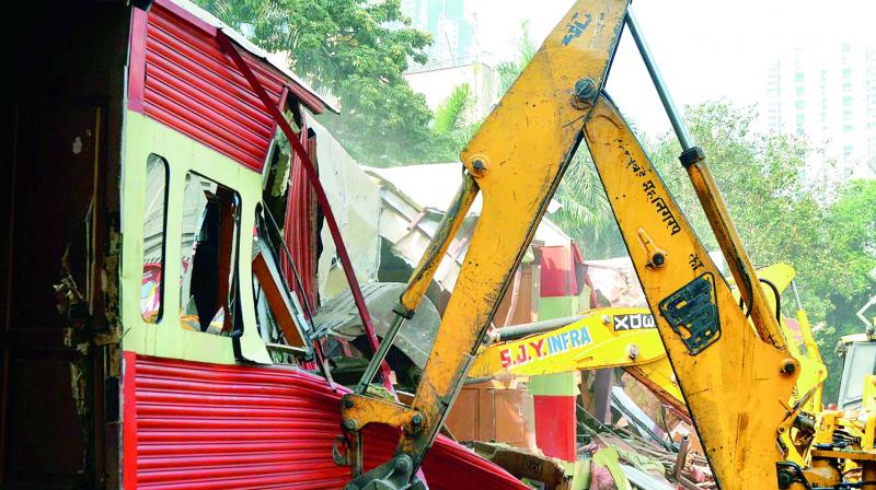 A bulldozer takes down illegally constructed eateries in the Kamala Mills compound following the fire incident, in Mumbai on Saturday. (Photo: PTI)