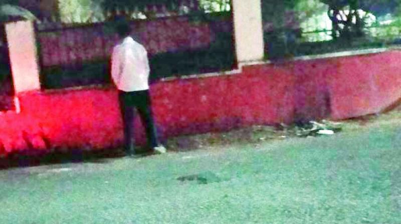 A man pees at the side of the road in the posh Cyberabad area.