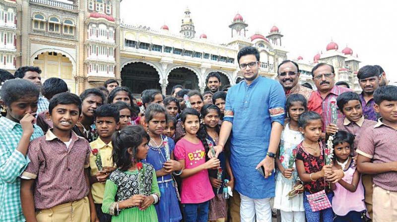 Mysuru scion Yaduveer Krishnadatta Chamaraja Wadiyar with schoolchildren in front of Mysuru Palace on Tuesday .