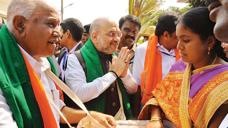 BJP national president Amit Shah and state president B.S. Yeddyurappa collect rice as part of the partys Mushti Dhanya Abhiyana in Davanagere on Tuesday.