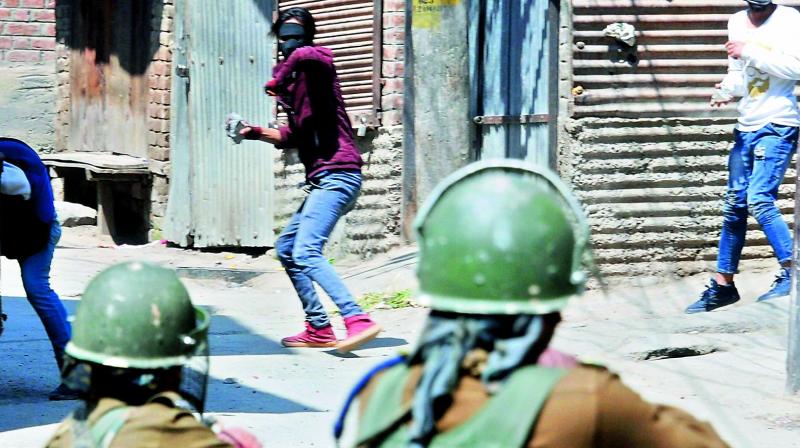 A man throws stones on security personnel during clashes following Shopian encounters, in Srinagar on Sunday. (Photo: PTI)