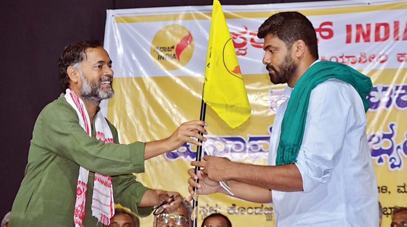 Swaraj India president Yogendra Yadav presents a party flag to Darshan in Mandya on Wednesday. (Photo: DC)