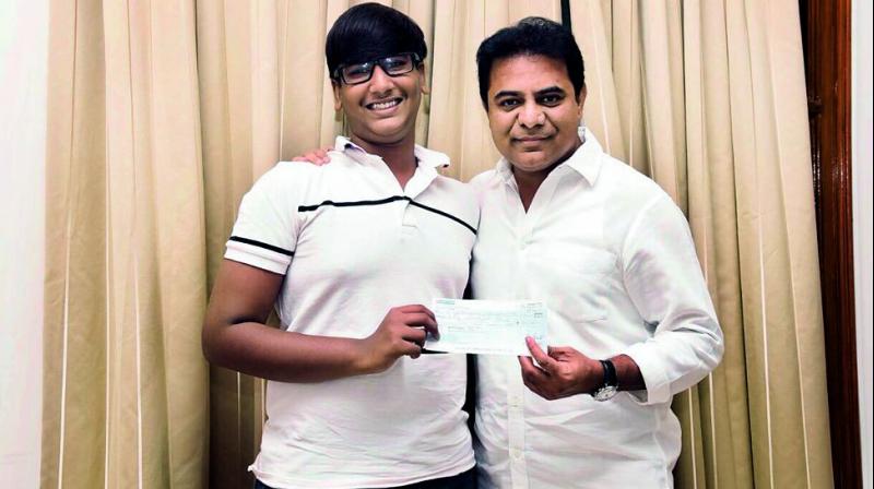 Sai Vishruth Reddy, a class X student of Future Kids International School, hands over a cheque for 50,000 to Minister for IT & Municipal Administration K.T. Rama Rao on Tuesday. (Photo: DC)