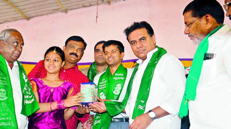 A girl in Mustafanager donates Rs 30,000 that she had saved over the years to  minister K.T. Rama Rao for the Rythu Bandhu Scheme on Friday. (Photo: DC)