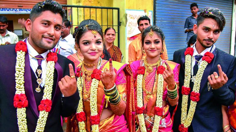 Two newly-married couples show their ink-marked fingers after casting their votes for Karnataka Assembly elections in Hubbali on Saturday. 	(Photo: PTI)