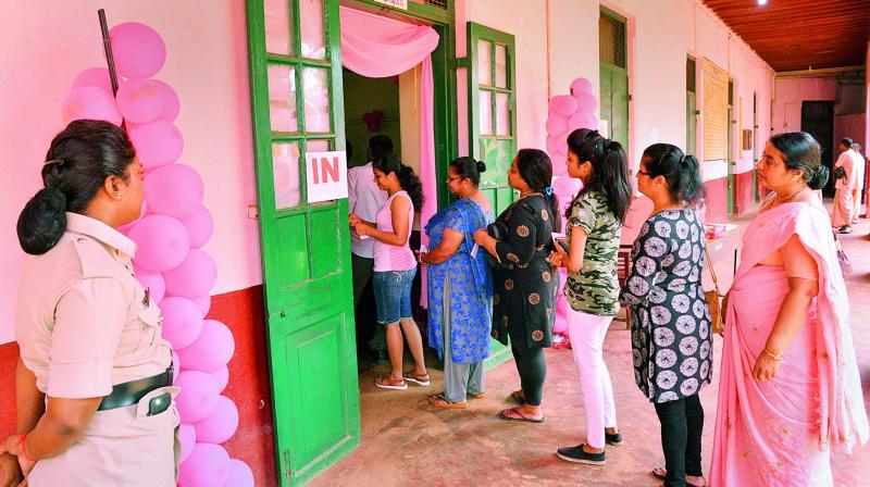 Voters stand in a queue to cast their votes at a polling station in Mangaluru on Saturday. (Photo: PTI)
