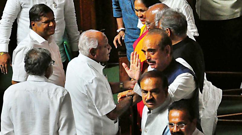 Outgoing Chief minister and BJP leader B.S. Yedyurappa shaking the hands of opposition leader Mallikarjun Kharge as he leaves the House on Saturday. (Photo: DC)