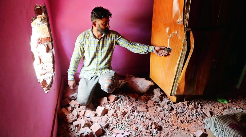 An villager inspects a hole made in a wall of a residential house by a mortar shell firing allegedly from Pakistan, at Gol pattan in Kanachack sector near Jammu on Sunday. (Photo: AP)
