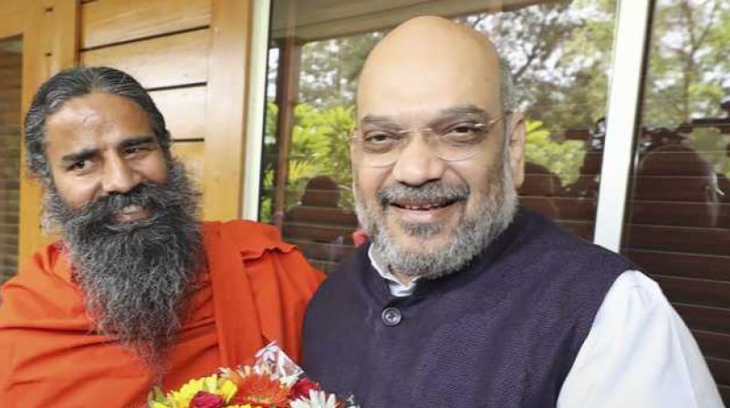 BJP chief Amit Shah meets yoga guru Baba Ramdev during his campaign to create awareness about the NDA governments achievements, in New Delhi. (Photo: PTI)