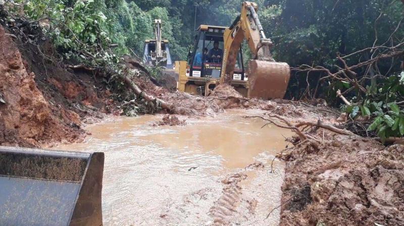 Workers use an earth mover to clear the piles of mud from the road at Charmadi Ghat.