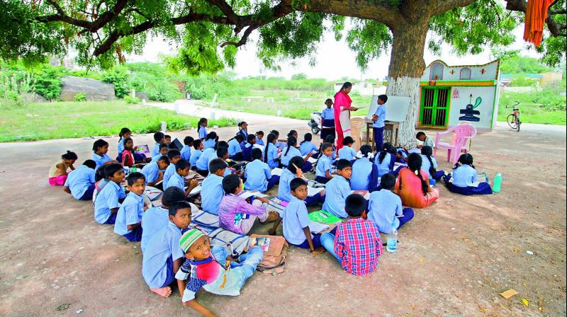 A teacher takes a class for the students under the shadow of a tree due to lack of classrooms at the government primary school at Middle Fort in Warangal Urban district.