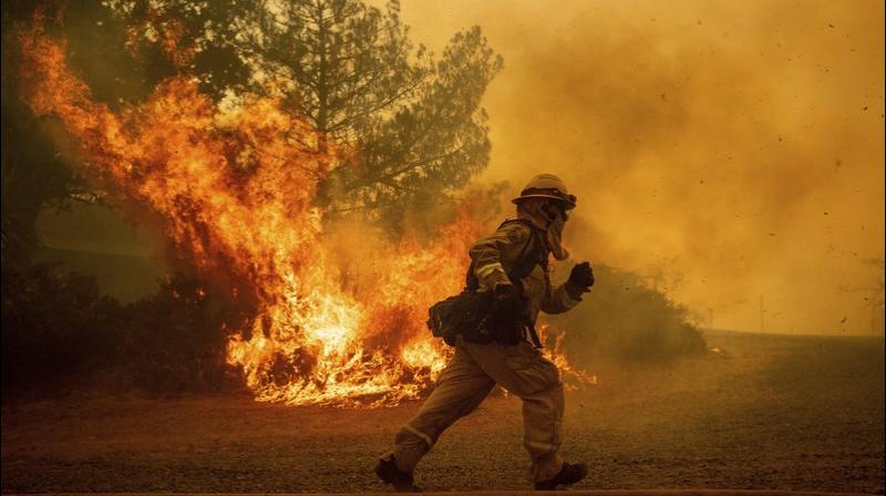 A firefighter runs while trying to save a home as a wildfire tears through Lakeport, Calif. The residence eventually burned. (Photo: AP)