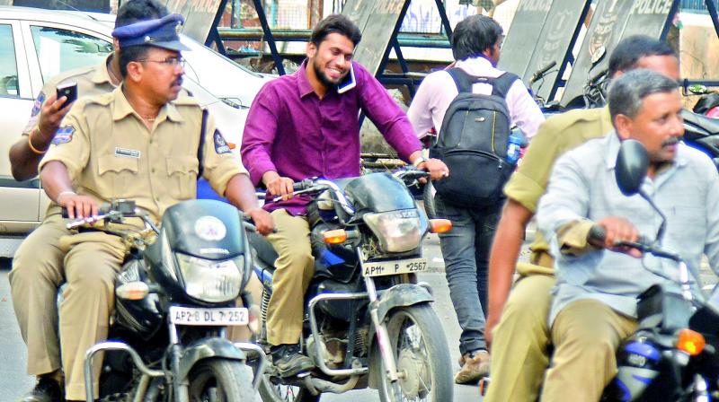 Cops return from a briefing on security arrangements for the Opposition-sponsored Chalo Dharna Chowk rally without wearing helmets and one of them even talking on the phone while riding his bike. (Photo: S. Surender Reddy)
