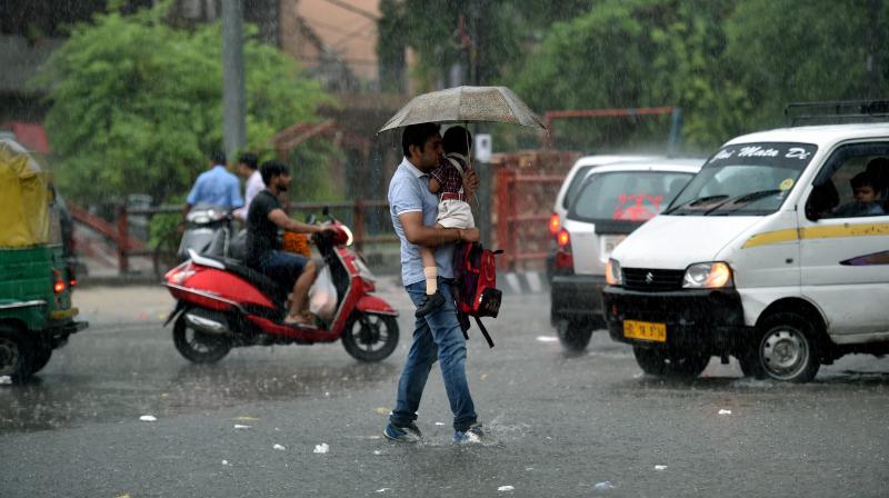 A pedestrian walks across a waterlogged street in the pouring rain on Thursday. (Photo: PTI)