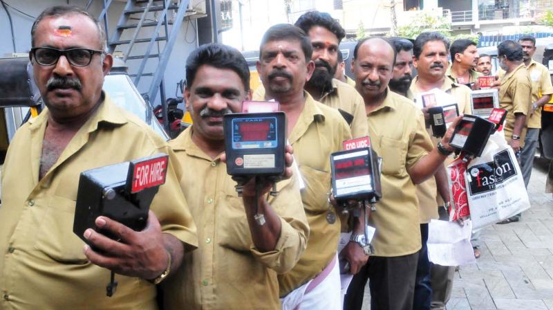 Auto drivers hold auto-fare meters in front of a licensed repairing agency for recalibrating new fares near Vanross Junction. (Photo: A.V.MUZAFAR)