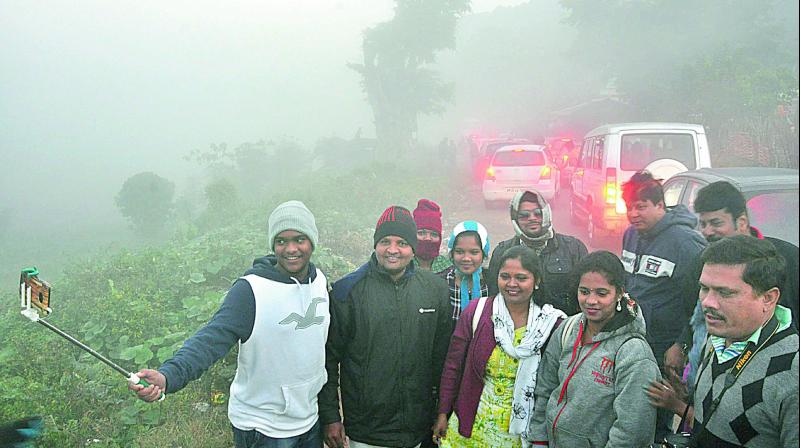 Tourists take a selfie at Lammasingi in Chintapalle mandal in Visakhapatnam district on Tuesday.