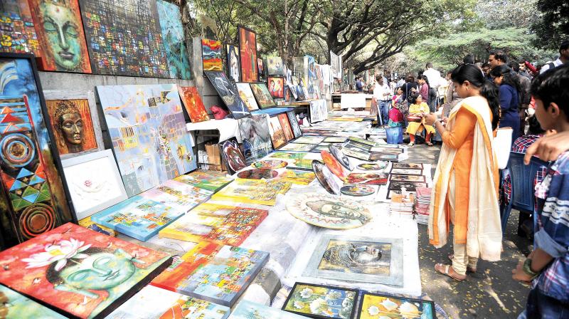 People throng the annual fair of exhibits, art work and art performance at Chitra Sante at Karnataka Chitrakala Parishath on Kumara Krupa Road in Bengaluru on Sunday. (Photo: DC)