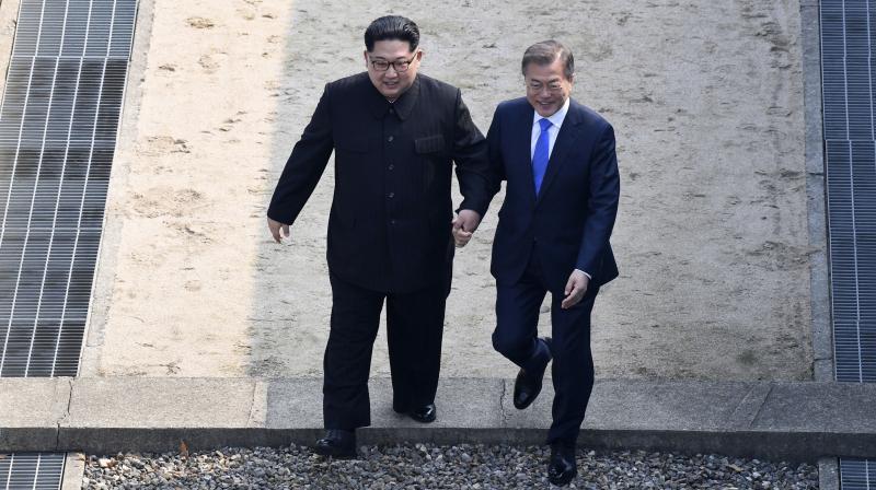 North Korean leader Kim Jong Un, left, and South Korean President Moon Jae-in cross the military demarcation line to the South side at the border village of Panmunjom in the Demilitarized Zone Friday. (Photo: AP)