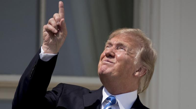 US President Donald Trump points at the sun as he views the solar eclipse at the White House.