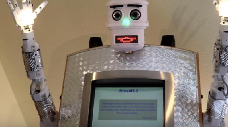 The metallic-bodied robot has a screen that asks people about the blessings they want and then raises its hands and smiles just like the priest does. (Photo: Youtube)