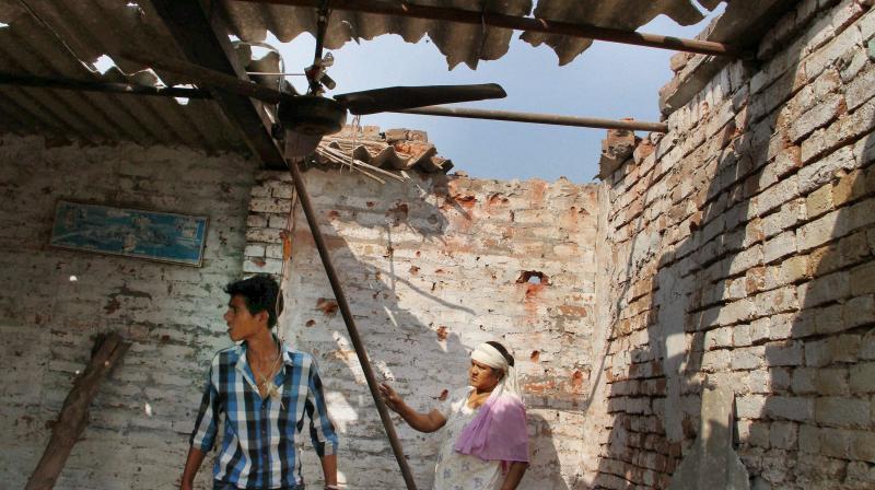 Villagers show a damaged roof house due to alleged shelling from across the LoC at the India-Pakistan International border in Bidipur village of RS Pura sector, Jammu. (Photo: PTI)