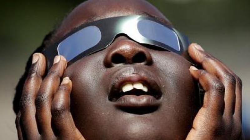 In this photo taken Friday, Aug. 18, 2017, Poureal Long, a fourth grader at Clardy Elementary School in Kansas City, Mo., practices the proper use of eclipse glasses in anticipation of Mondays solar eclipse. Schools around the country preparing for the solar eclipse are reacting in a variety ways, with some using the event for a full day of science lessons and others closing to avoid the crush of crowds expected in their towns. (AP Photo/Charlie Riedel)