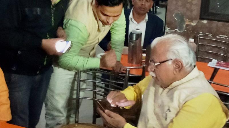 Haryana Chief Minister Manohar Lal Khattar making online payment through his mobile phone after taking tea at a shop near bus stand in Karnal. (Photo: PTI)