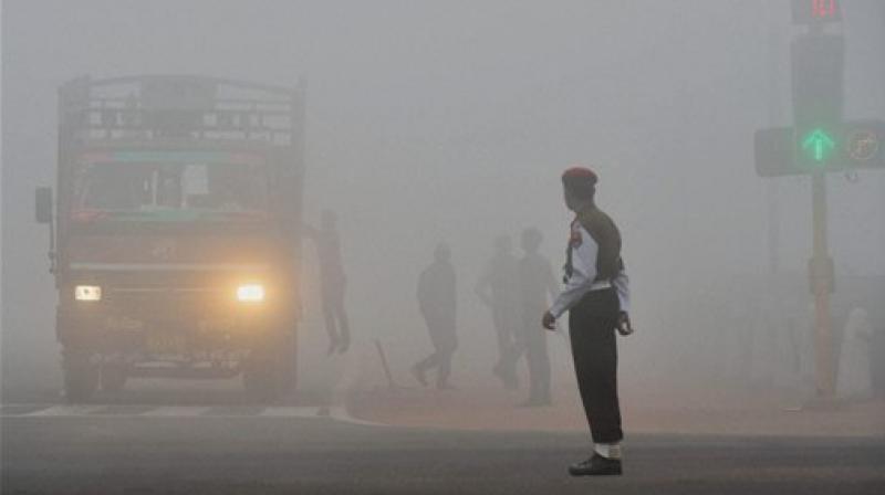 : A truck, with its headlights on, seen in dense fog at the Rajpath in New Delhi. (Photo: PTI)