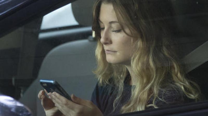 In this Wednesday, June 22, 2016, file photo, a driver uses her mobile phone while sitting in traffic in Sacramento, Calif. The government wants smartphone makers to lock out most apps when the phone is being used by someone driving a car. The voluntary guidelines unveiled Wednesday, Nov. 23, 2016, are designed to reduce crashes caused by drivers distracted by phones. (AP Photo/Rich Pedroncelli, File)