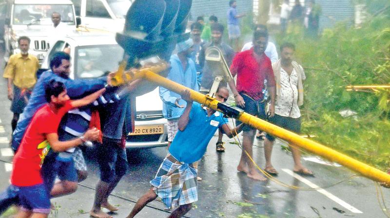 People lifting uprooted poles following a storm in Chennai on Monday. The movement of traffic on  several arterial roads including the famous Anna Salai, Grand Southern Trunk road were  largely affected while several trees were also uprooted as cyclone Vardah made landfall near Chennai coast on Monday.