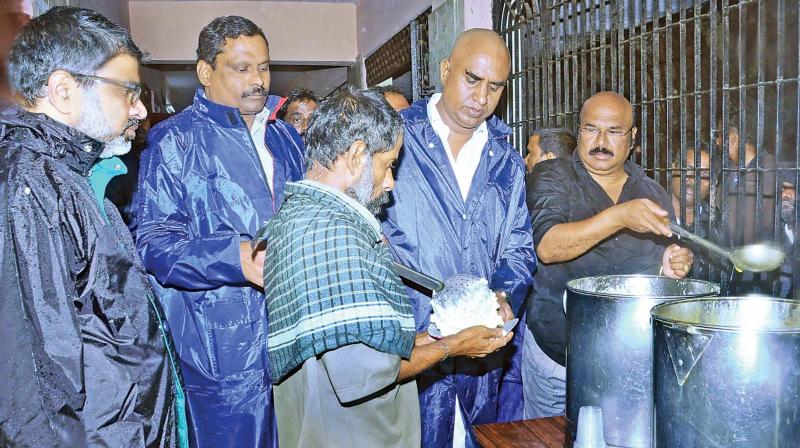Tamil Nadu fisheries minister D. Jayakumar (right) and municipal administration minister S.P. Velumani (second from right) provide food to those affected by Vardah cyclone at Nochikuppam on Tuesday (Photo: DC)