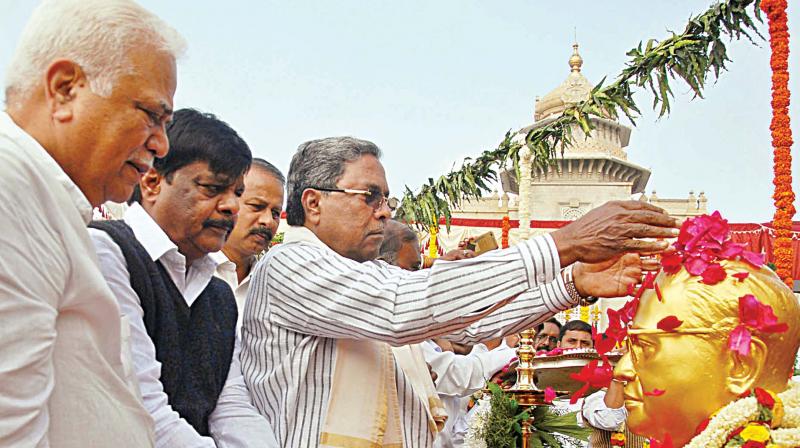 Chief Minister Siddaramaiah garlands the statue of Dr B.R. Ambedkar at Vidhana Soudha in Bengaluru on Wednesday as ministers RV Deshpande and Dr H.C. Mahadevappa look on. (Photo: DC)