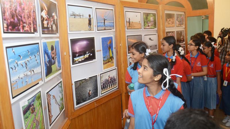 School students take a look at photographs put up by the Vizag Photo Journalists Association to mark the 177th World Photography Day in Visakhapatnam on Saturday. (photo: DC)