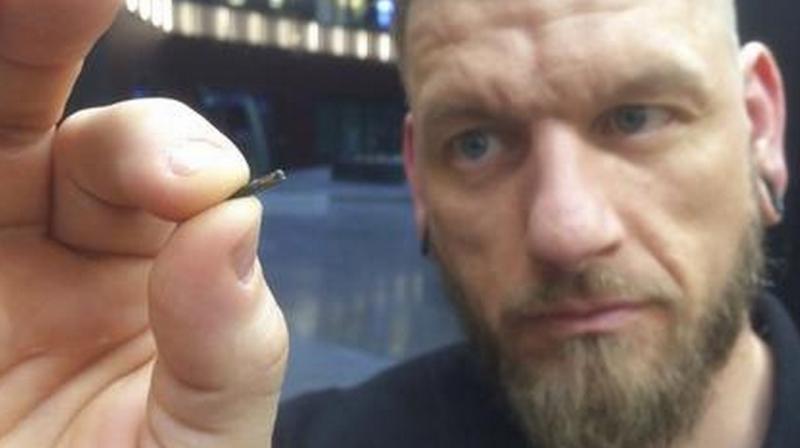 Self-described â€œbody hackerâ€ Jowan Osterlund from Biohax Sweden, holds a small microchip implant, similar to those implanted into workers at the Epicenter digital innovation business centre during a party at the co-working space in central Stockholm, Tuesday March 14, 2017. Microchips are being implanted into volunteers to help them open doors and operate office equipment, and its become so popular that members of the Epicentre cyborg club hold regular parties for those with the tiny chips embedded in their hands. (AP Photo/James Brooks)