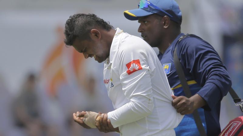 Asela Gunaratne grimaces in pain after being injured during the first days play of the first test cricket match between India and Sri Lanka in Galle. (Photo: AP))