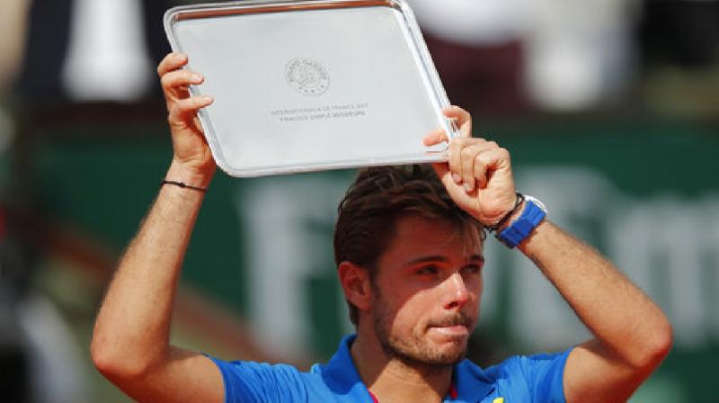 Switzerlands Stan Wawrinka holds the runner-up trophy after losing to Spains Rafael Nadal in three sets, 6-2, 6-3, 6-1, during their mens final match of the French Open tennis tournament. (Photo: AP)