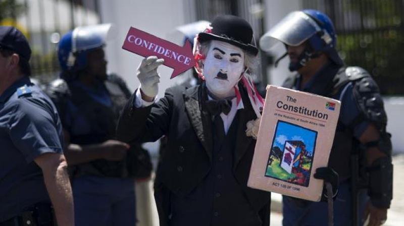 A protester dressed up as Charlie Chaplin and holding a picture of the South African constitution demonstrates outside the South African parliament before a no-confidence debate against President Jacob Zuma in Cape Town on November 10, 2016. (Photo: AFP)
