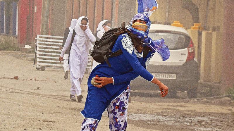 A student throws a stone at security personnel at Lal Chowk in Srinagar on Monday. (Photo: PTI)