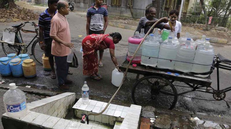 A water vendor and residents of an area take drinking water from a roadside water source in Kolkata (Photo: AP)