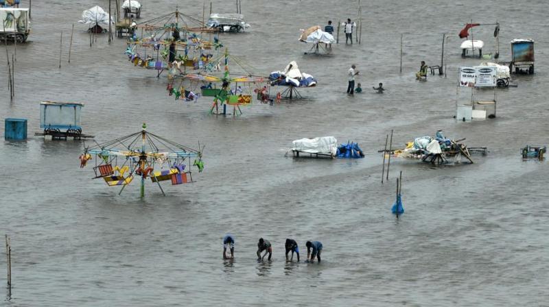 People walk through a flooded area of Marina Beach on the Bay of Bengal coast after heavy rains lashed Chennai for the eighth day. (Photo: AFP)