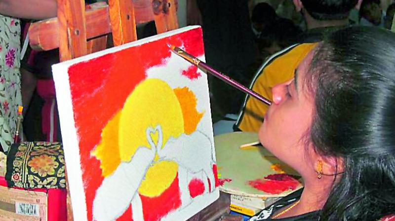 Srilekha painting with a brush in her mouth.