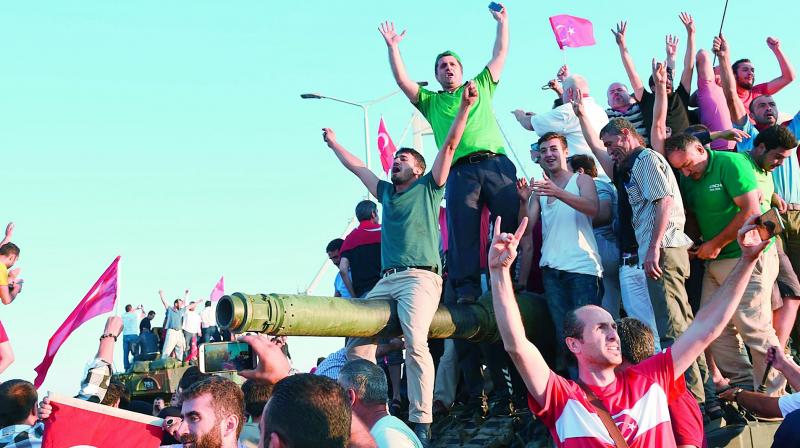 People rally on a tank after they take over military position on the Bosphorus bridge in Istanbul after an attempted coup failed on July 16, 2016. Many coup plotters had fled to Greece. (Photo: AFP)