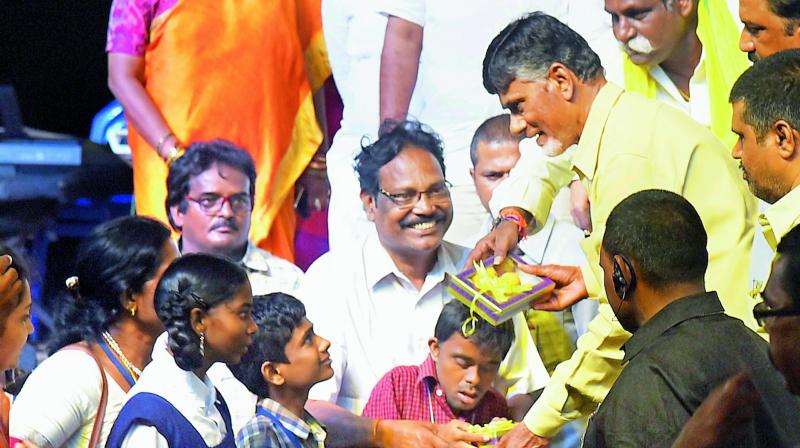 Chief Minister Nara Chandrababu Naidu distributes sweets to children celebrating Ananda Deepavali at R.K. Beach in Visakhapatnam on Tuesday. (Photo: DC)