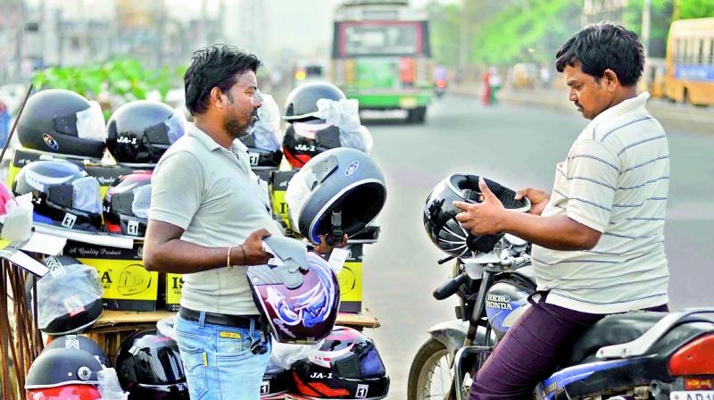 A motorist bargains with a roadside vendor to purchase a helmet in Guntur. (Photo: DC)