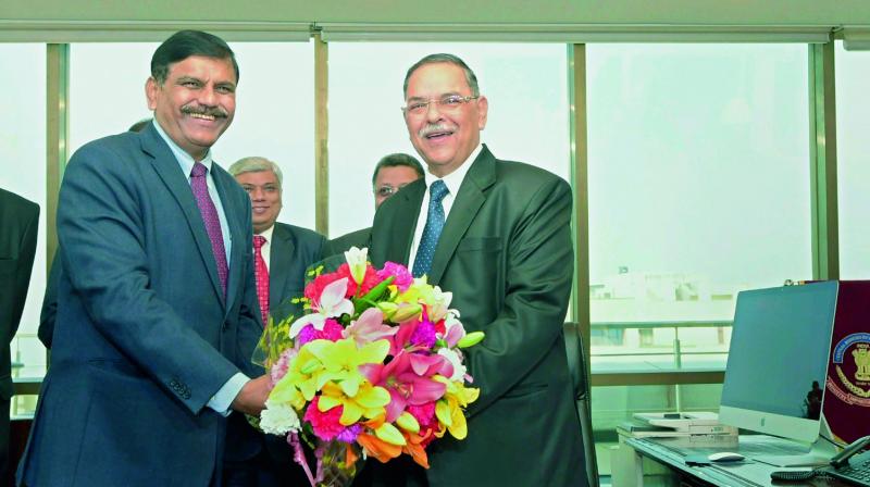 Interim Central Bureau of Investigation (CBI) chief M. Nageswara Rao presents a  bouquet to the newly-appointed CBI chief Rishi Kumar Shukla as he takes charge at CBI headquarters, in New Delhi on Monday. 	(PTI)