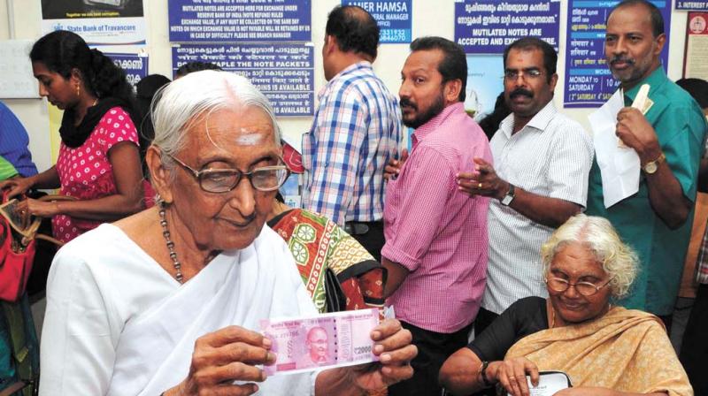 An elderly woman shows the newly-introduced Rs 2000 currency note at SBT main branch in Thiruvananthapuram.