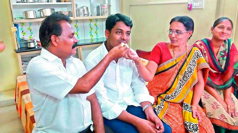 Gorantla Jayanth Harsha from Guntur, who bagged the first rank in engineering being fed sweets by his parents at their home on Monday.