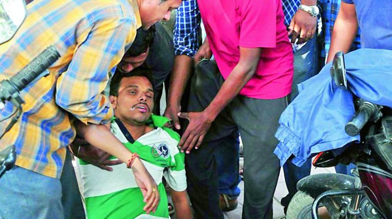 People help a person, who fainted while standing in a queue at a bank ATM at Padmaraonagar in Hyderabad on Thursday. (Photo: Deepak Despande)