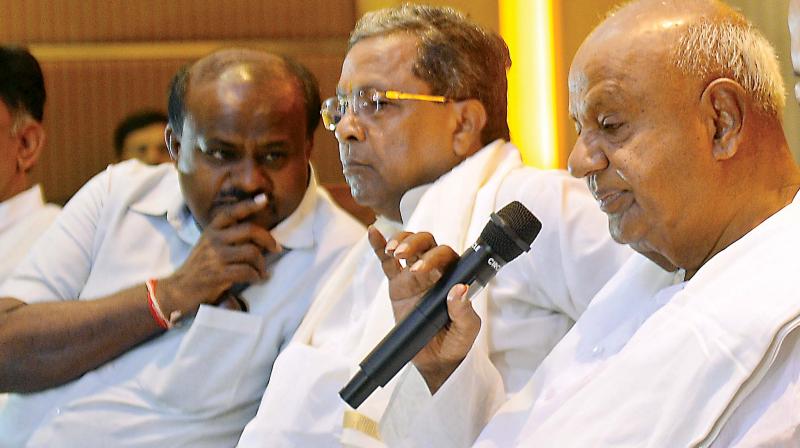 CM H.D. Kumaraswamy has a word with former CM Siddaramaiah even as former PM H.D. Deve Gowda speaks at Congress-JD(S) press meet in Bengaluru on Saturday. (Sathish B.)